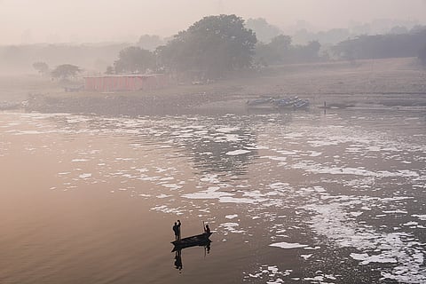A fisherman rows a boat through toxic foam near Kalindi Kunj, in New Delhi.