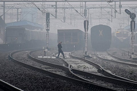 A man crosses a railway track amid dense fog on a winter morning, in Prayagraj.
