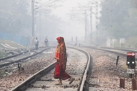 A woman crosses railway tracks amid low visibility on a winter day, in Gurugram.
