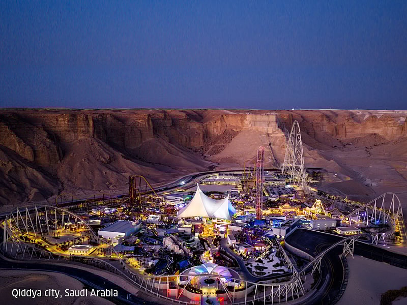 Aerial night view of Qiddiya City with illuminated attractions and desert surroundings.