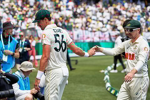 Australia's Mitchell Starc, left, is congratulated by teammate Travis Head as he eaves the ground after England is bowled out during the first Ashes cricket test match between Australia and England in Perth.