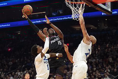 Phoenix Suns center Mark Williams (15) goes up to shoot over Minnesota Timberwolves forward Jaden McDaniels (3) and center Rudy Gobert, right, during the first half of an NBA Cup basketball game in Phoenix. 