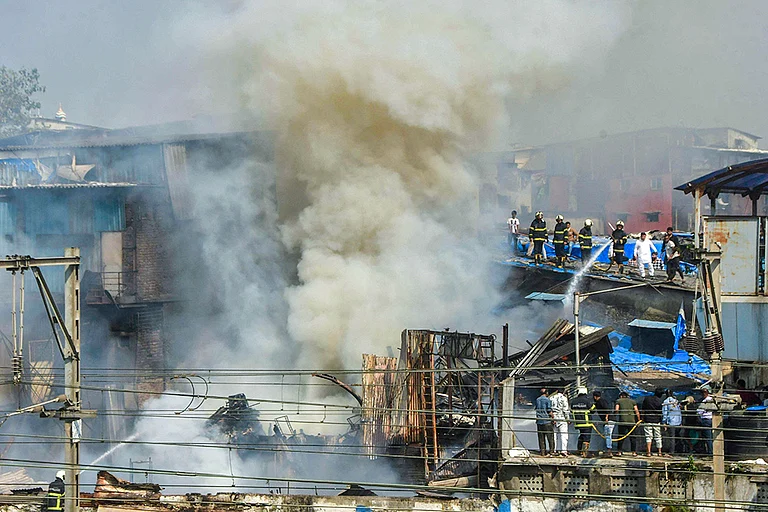 Smoke billows as firemen douse a fire breaking out in huts close to the Harbour line local train tracks at Dharavi area, in Mumbai, Maharashtra. - | Photo: PTI