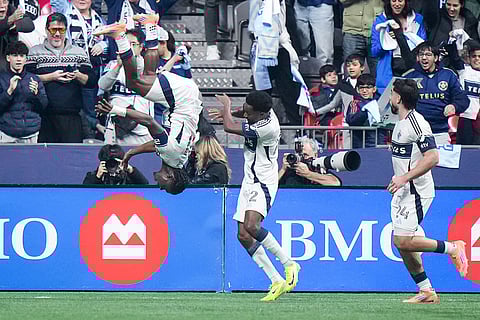 Vancouver Whitecaps' Emmanuel Sabbi, left, flips after his goal with Ali Ahmed, center, and Brian White,  right, during the first half of the MLS Western Conference semifinal soccer match against Los Angeles FC in Vancouver, British Columbia.
