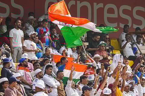 Fans wave the national flag during the day two of the second Test cricket match of a series between India and South Africa, at ACA Stadium in Guwahati.