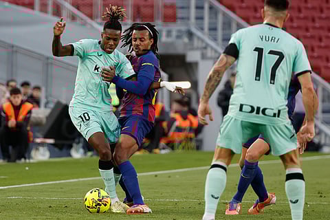 Athletic Bilbao's Nico Williams, left, and Barcelona's Jules Kounde fight for the ball during a La Liga soccer match between Barcelona and Athletic in Barcelona, Spain.