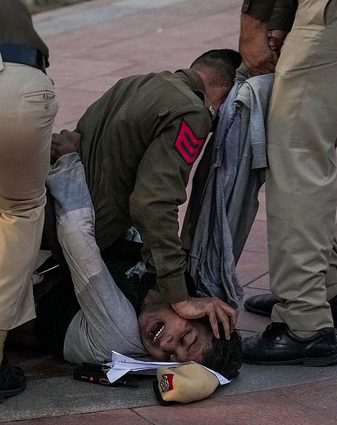 Police personnel detain a protestor during a protest against worsening air quality in the national capital, near the India Gate, in New Delhi.