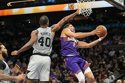 Phoenix Suns guard Devin Booker (1) shoots under San Antonio Spurs forward Harrison Barnes (40) during the second half of an NBA basketball game in Phoenix.