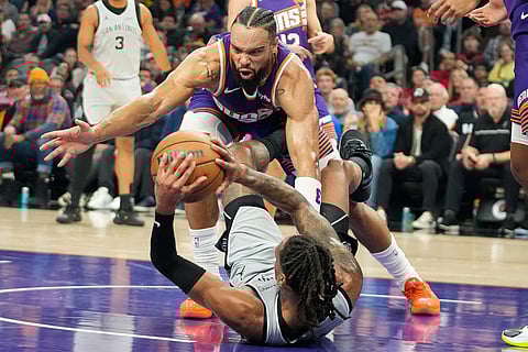 Phoenix Suns forward Dillon Brooks, top, goes for a loose ball against San Antonio Spurs guard Devin Vassell, bottom, during the first half of an NBA basketball game in Phoenix.