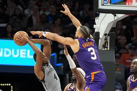 San Antonio Spurs guard De'Aaron Fox (4) looks to pass as Phoenix Suns forward Dillon Brooks (3) puts pressure on him during the second half of an NBA basketball game in Phoenix.