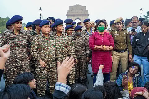 Police and security personnel stand guard as people protest against worsening air quality in the national capital, at the India Gate, in New Delhi.