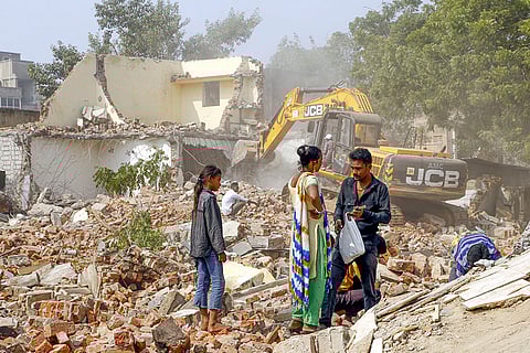 People stand amid debris of demolished structures after an anti-encroachment drive in the Isanpur area, Ahmedabad.