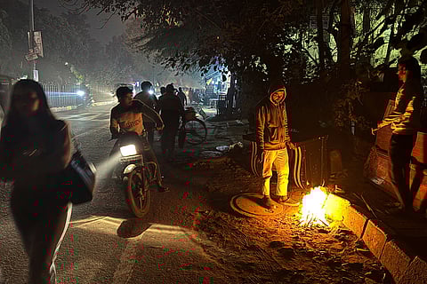 Commuters pass bonfires lit to combat the cold while the capital's air quality remains grim, hovering near the 'severe' category, in New Delhi.
