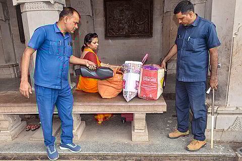 Security personnel check luggage of a visitor at Vindhyavasini Temple that received a bomb threat, in Mirzapur.