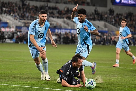 San Diego FC forward Corey Baird (21) goes down in front of Minnesota United defender Michael Boxall (15), left, and Carlos Harvey (67) during the first  half of MLS soccer's Western Conference semifinal in San Diego. 