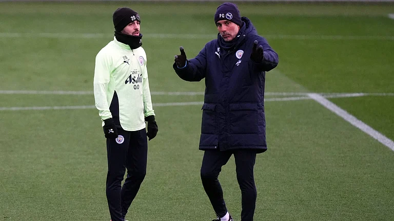Manchester City's manager Pep Guardiola talks with Bernardo Silva during a training session on November 24, 2025, ahead of the UEFA Chamoions League match against Bayer 04 Leverkusen. - | Photo: PA/Mike Egerton via AP
