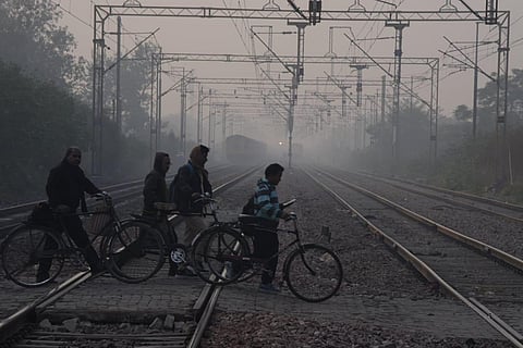 People cross railway tracks on a smoggy day in Faridabad.