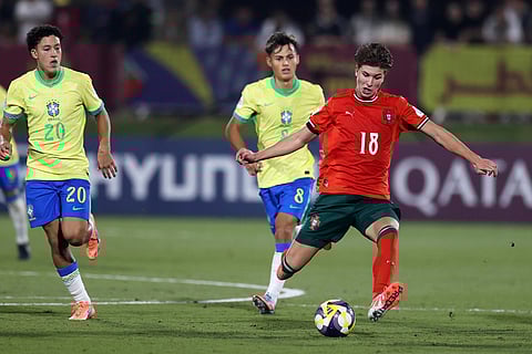 Portugal's Bernardo Lima fights for the ball against Brazil's Felipe Morais and Tiago during the FIFA U17 World Cup semifinal soccer match between Portugal and Brazil in Doha, Qatar.