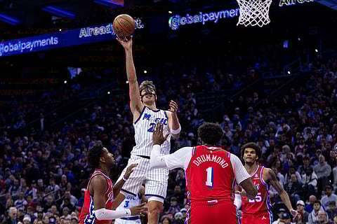 Orlando Magic's Franz Wagner, top, shoots the ball over Philadelphia 76ers' Justin Edwards, left, and Andre Drummond (1) during the first half of an NBA Cup basketball game in Philadelphia.
