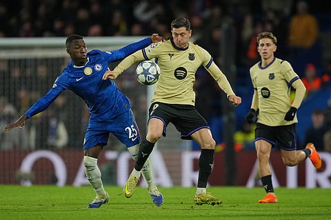 Barcelona's Robert Lewandowski, center, is challenged by Chelsea's Moises Caicedo during the Champions League opening phase soccer match between Chelsea and Barcelona in London.