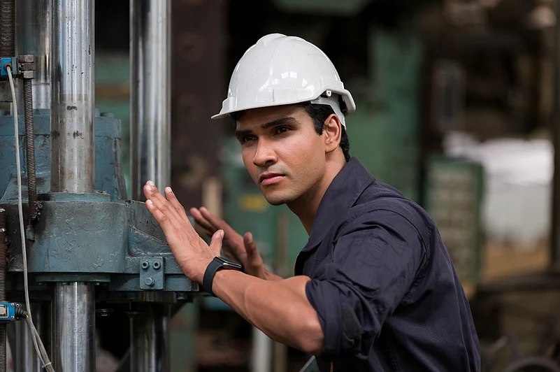 Man in a white hard hat working with industrial machinery