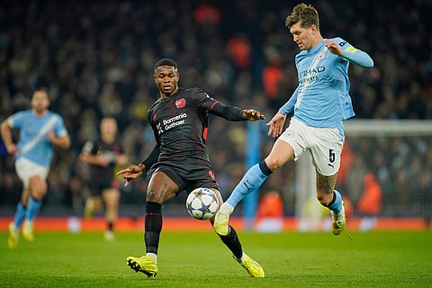 Leverkusen's Jeanuel Belocian, left vies for the ball with Manchester City's John Stones during the Champions League opening phase soccer match between Manchester City and Bayer Leverkusen in Manchester, England.