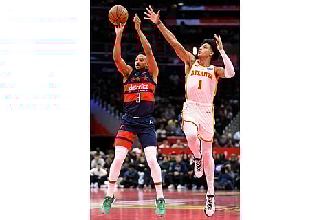 Washington Wizards guard CJ McCollum (3) hits a three-point shot against Atlanta Hawks forward Jalen Johnson during the first half of an NBA Cup basketball game in Washington.