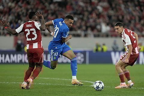 Real Madrid's Kylian Mbappe, centre, dribbles past Olympiacos' Rodinei during the Champions League opening phase soccer match between Olympiacos and Real Madrid, in in Piraeus port, near Athens, Greece.