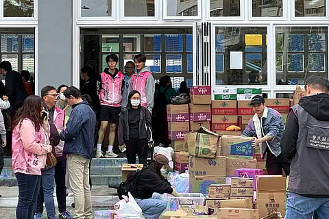 Volunteers arrange donated supplies including water and snacks at Church of Christ in China Fung Leung Kit Memorial Secondary School, a temporary evacuation center set up after the fire at several high-rise towers that started Wednesday. 