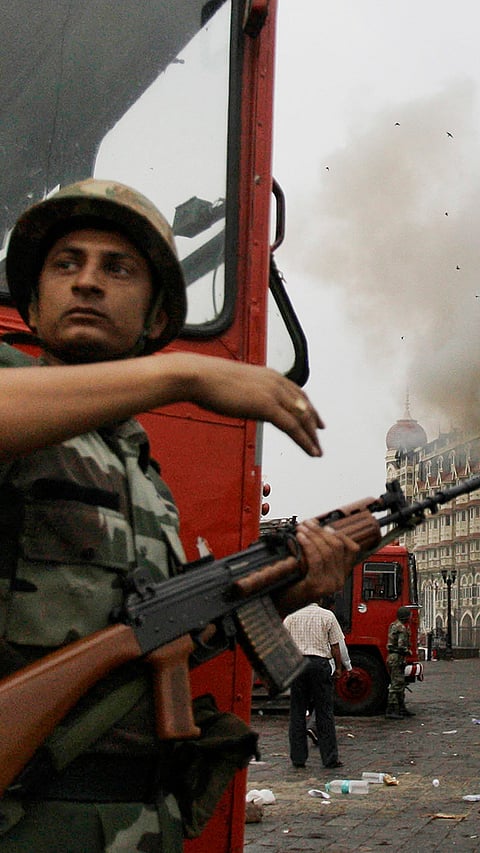 An Indian soldier takes cover as the Taj Mahal hotel burns