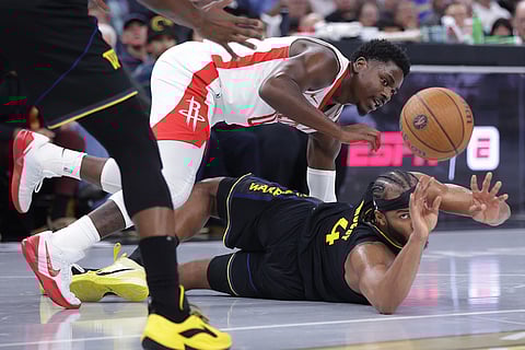 After securing a loose ball, Golden State Warriors' Moses Moody passes against Houston Rockets' Aaron Holiday during the second half of an Emirates NBA Cup basketball game in San Francisco.