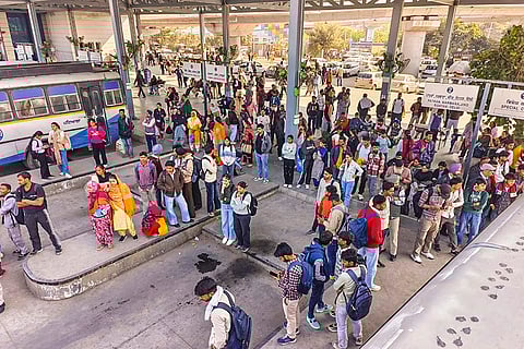 Commuters wait in queues for a PRTC bus after police detained protesting members of the PRTC Contract Employees Union, in Patiala.
