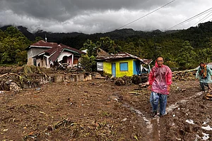 | Photo: AP/Ade Yuandha : People walk past damaged houses at a village affected by flood in Malalak, West Sumatra, Indonesia.