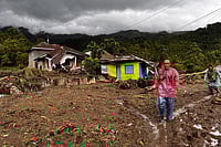 | Photo: AP/Ade Yuandha : People walk past damaged houses at a village affected by flood in Malalak, West Sumatra, Indonesia.