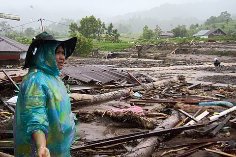 A woman inspects the damage after a flood in Malalak, West Sumatra, Indonesia.