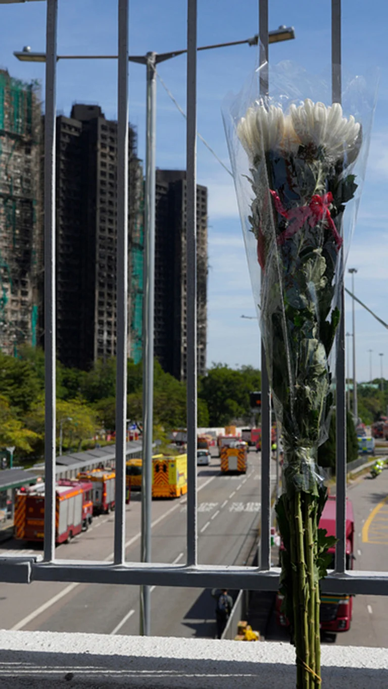 A bouquet of flower is placed at an overhead bridge near the site of a fire at Wang Fuk Court, a residential estate in the Tai Po district of Hong Kong's New Territories. - | Photo: AP/Ng Han Guan