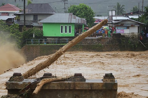 In this photo released by Indonesia's National Disaster Management Agency (BNPB) residents inspect a road cut off by a flood in Padang, West Sumatra, Indonesia. 