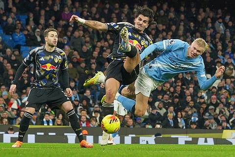 Manchester City's Erling Haaland, right, challenges for the ball with Leeds' Pascal Struijk during the English Premier League soccer match between Manchester City and Leeds United in Manchester, England.