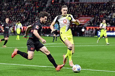 Bayer's Jonas Hofmann, and Borussia's Nico Schlotterbeck fight for the ball during the German Bundesliga soccer match between Bayer Leverkusen and Borussia Dortmund in Leverkusen, Germany.