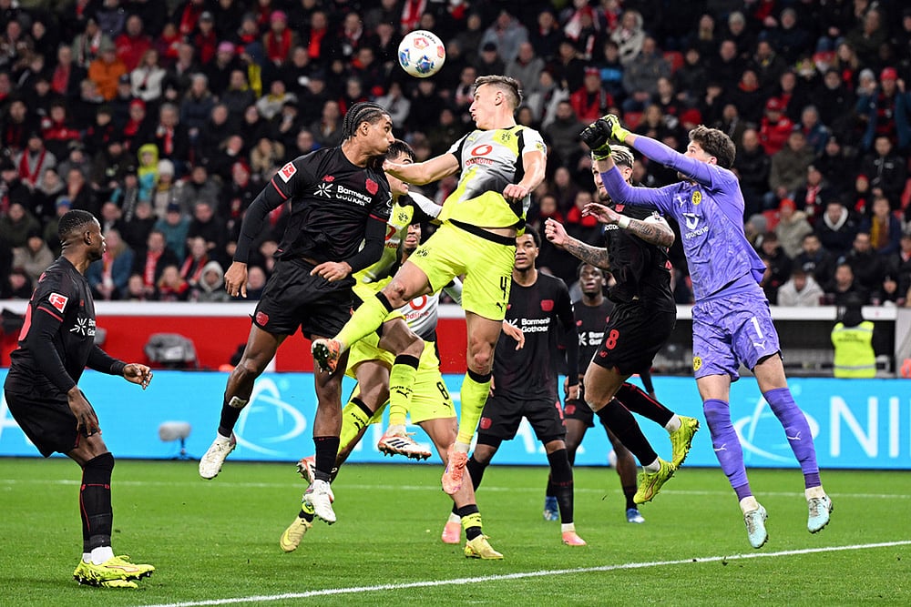 Bayer's Loïc Badé, center left, and Borussia's Nico Schlotterbeck fight for the ball during the German Bundesliga soccer match between Bayer Leverkusen and Borussia Dortmund in Leverkusen, Germany. - | Photo: Federico Gambarini/dpa via AP
