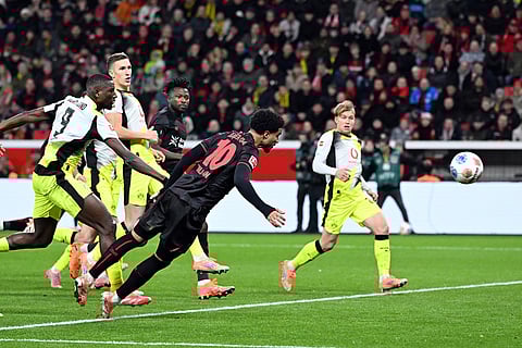 Bayer's Malik Tillman, center, and Borussia's Serhou Guirassy fight for the ball during the German Bundesliga soccer match between Bayer Leverkusen and Borussia Dortmund in Leverkusen, Germany.