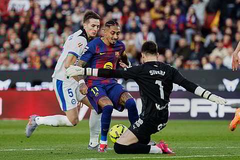 Barcelona's Raphinha, center, tries a shot with Alaves' goalkeeper Antonio Sivera during a Spanish La Liga soccer match between Barcelona and Alaves, in Barcelona, Spain.