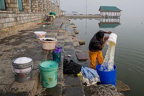 A man washes clothes on a cold morning, at Dal Lake in Srinagar. The city recorded a minimum temperature of -4.4 degrees Celsius on Saturday night. 