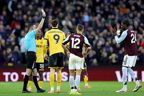 Wolverhampton Wanderers' Jhon Arias, obscured, is shown a yellow card by referee Christopher Kavanagh, during the English Premier League soccer match between Aston Villa and Wolverhampton Wanderers, at Villa Park, in Birmingham, England.