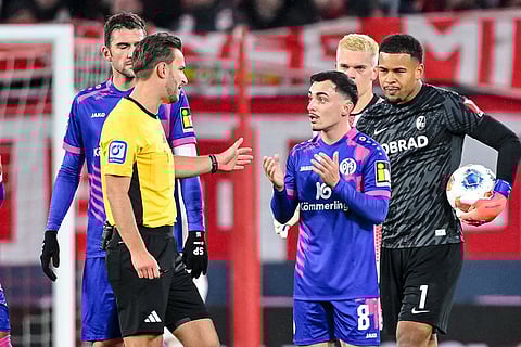 Referee Benjamin Brand, left gestures after showing Paul Nebel of 1. FSV Mainz 05 the red card, during a German Bundesliga soccer match between SC Freiburg and 1. FSV Mainz 05, in Freiburg im Breisgau, Germany.