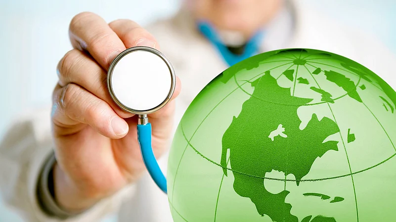A doctor with a stethoscope pointed towards a green globe