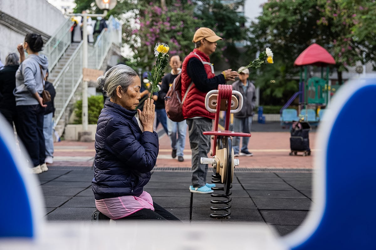People holds flowers and prays near the scene after the deadly fire that started Wednesday at Wang Fuk Court, a residential estate in the Tai Po district of Hong Kong's New Territories, Saturday Nov. 29, 2025.  - Chan Long Hei