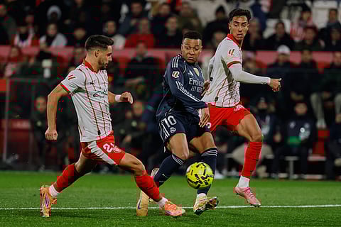 Real Madrid's Kylian Mbappe, center, vies for the ball with Girona's Alex Moreno during a Spanish La Liga soccer match between Girona and Real Madrid, in Girona, Spain.