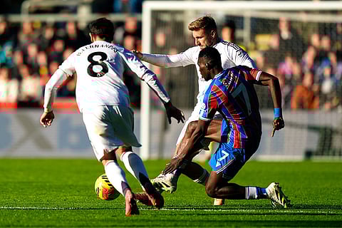 Crystal Palace's Ismaila Sarr is challenged by Manchester United's Bruno Fernandes, left, and Luke Shaw during the English Premier League soccer match between Crystal Palace and Manchester United in London.