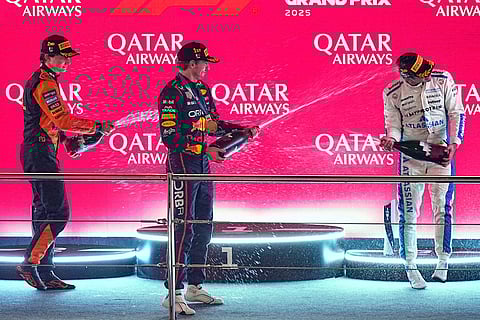 Winner Red Bull driver Max Verstappen of the Netherlands, centre, second placed McLaren driver Oscar Piastri of Australia, left, and third placed Williams driver Carlos Sainz of Spain celebrate on the podium after the Qatar Formula One Grand Prix, in Lusail, Qatar.